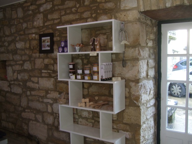 Shelving unit with patés and various kitchen tools.